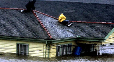Two Hurricane Katrina survivors find refuge on their roof as they await rescue