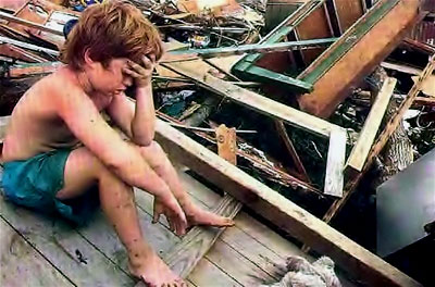 A distraught boy sits in disbelief amid the rubble