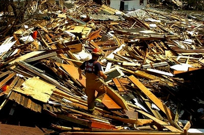 A firefighter walks atop destroyed houses